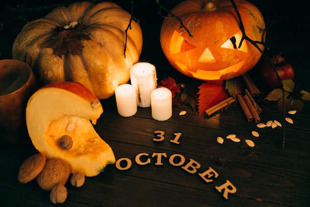 Holzschriftzug &quot;31. Oktober&quot; liegt vor großen Halloweenkürbis Kürbissen