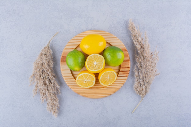 Holzteller mit frischen saftigen Zitronen auf Steintisch.