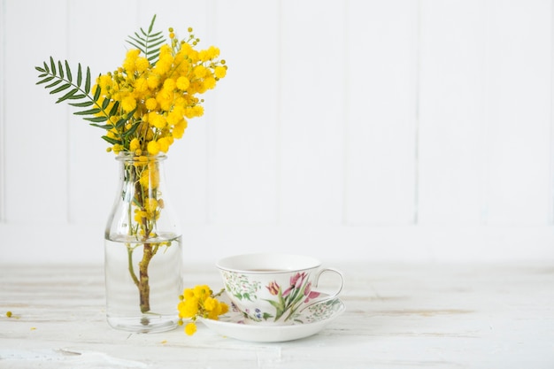 Holztisch mit einer Tasse Tee und Vase mit Blumen