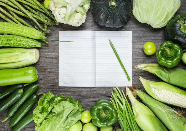 Holztisch mit grünem Gemüse und einem Notebook
