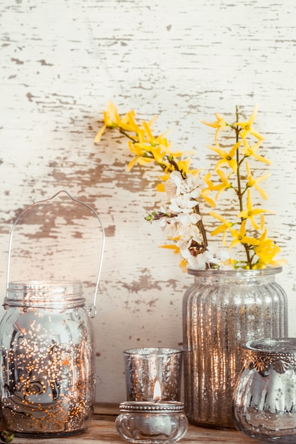 Kostenloses Foto home gemütliche schöne einrichtung, verschiedene vasen und kerzen mit frühlingsblumen, auf einem hölzernen hintergrund, das konzept der innendetails