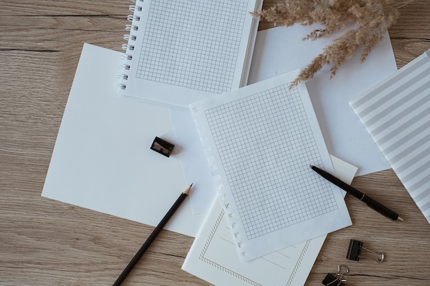 Home-office-schreibtischarbeitsplatz mit leeren papierblättern, notizbuch, pampasgras