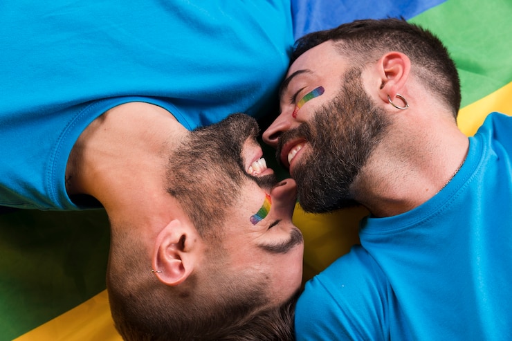Kostenlose Foto homosexuelle paare, die auf regenbogenflagge legen