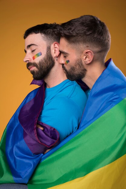Homosexuelle Paare, die liebevoll eingewickelt in der Regenbogenflagge umarmen