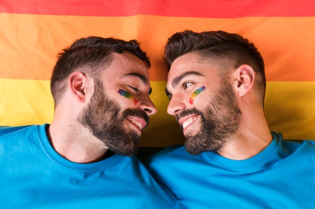 Homosexuelle Paare, die sich gegenseitig an Regenbogenflagge lehnen