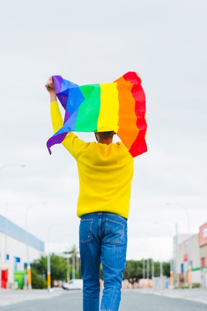 Homosexuelles Gehen auf der Straße, die LGBT-Flagge obenliegend hält