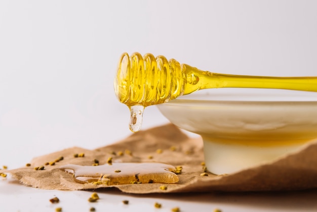 Kostenloses Foto honig, der vom schöpflöffel mit bienenpollen-samen auf braunem papier tropft