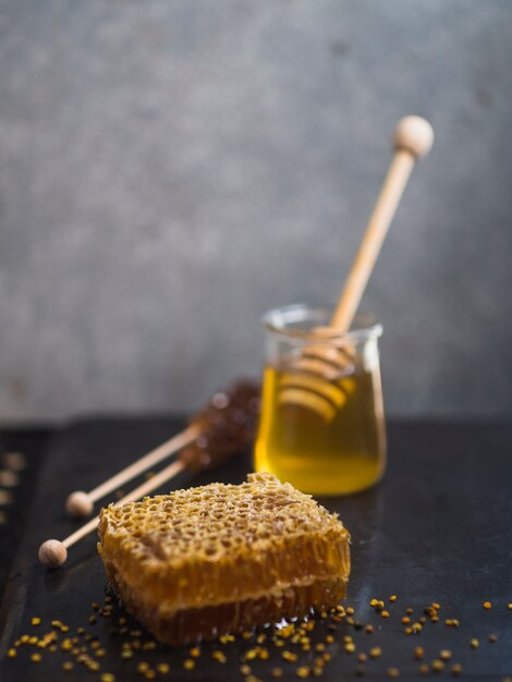 Honigkamm mit Honig; Holzlöffel und Blütenpollen