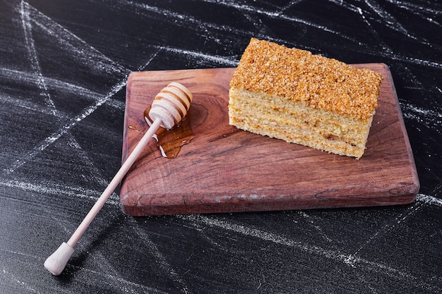 Honigkuchen mit Honiglöffel auf dunklem Hintergrund.