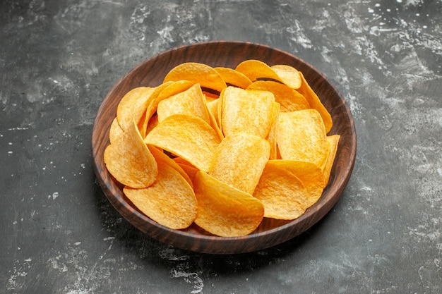 Kostenloses Foto horizontale ansicht der köstlichen hausgemachten kartoffelchips auf einem braunen teller auf grauem tisch