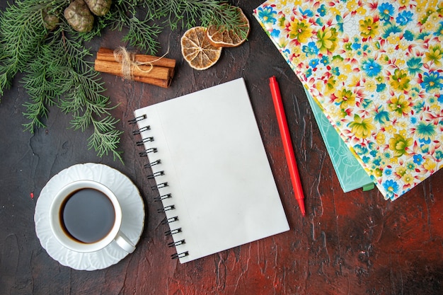 Horizontale Ansicht einer Tasse schwarzen Tee geschlossenes Notizbuch mit Stift-Zimt-Limonen, einem Ball aus Seil und Büchern auf dunklem Hintergrund