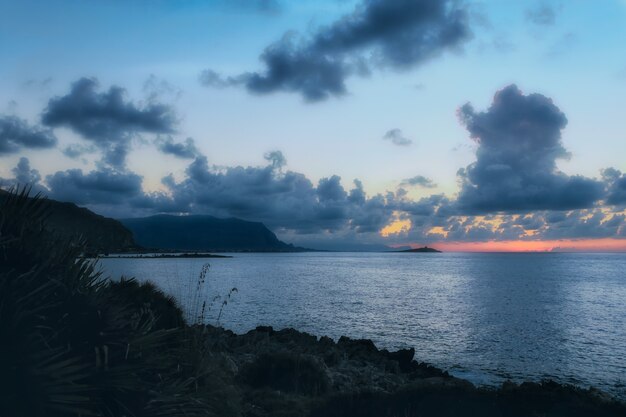 Horizontale Aufnahme des ruhigen Meeres unter dem verrückten bewölkten Himmel am Abend