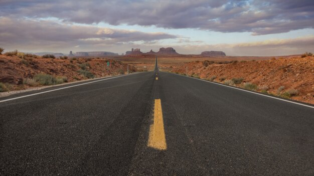 Horizontale Aufnahme einer leeren Straße im Monument Valley, USA mit dem Hintergrund des atemberaubenden Himmels
