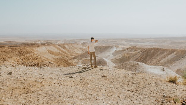 Horizontale Aufnahme eines Mannes mit einem weißen Hemd, das am Rand eines Berges steht, der die Ansicht genießt