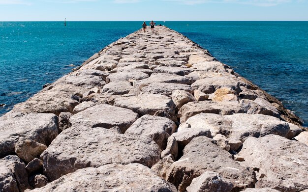 Horizontale Aufnahme eines Steinweges auf einem Gewässer mit Menschen, die darauf gehen.