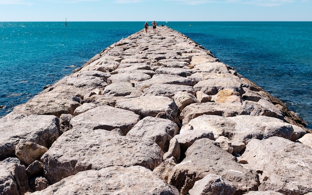 Horizontale Aufnahme eines Steinweges auf einem Gewässer mit Menschen, die darauf gehen.