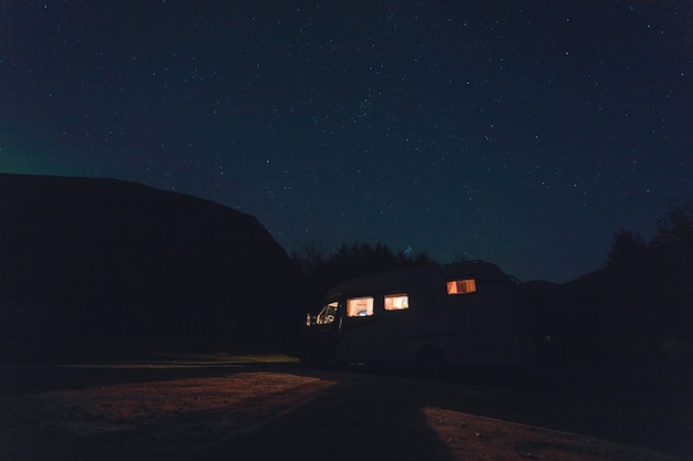 Horizontale Aufnahme eines weißen Fahrzeugs mit Lichtern unter dem schönen Sternenhimmel bei Nacht
