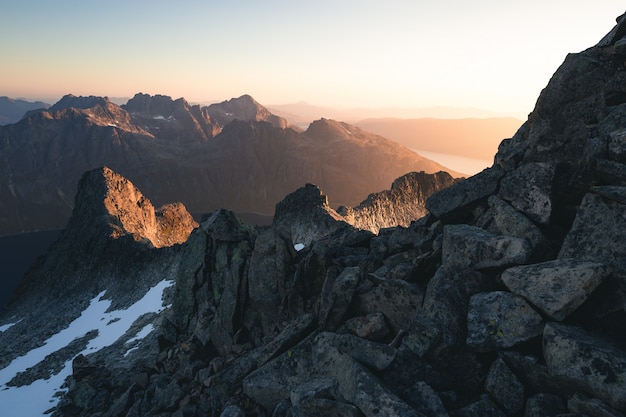 Horizontale Aufnahme von felsigen Bergen, die im Schnee während des Sonnenaufgangs bedeckt sind