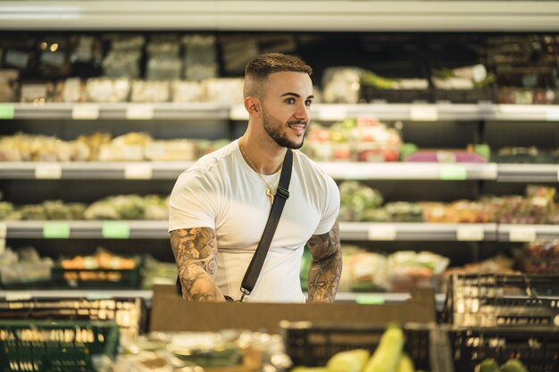 Horizontaler, flacher Fokus eines Mannes, der glücklich etwas im Supermarkt anschaut
