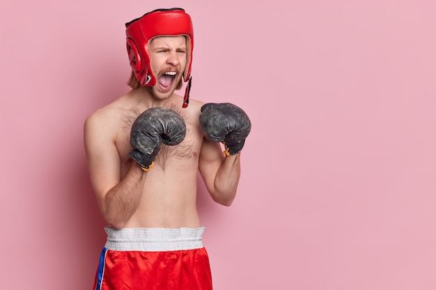 Kostenloses Foto horizontaler schuss des wütenden boxers schreit laut züge im fitnessstudio bereitet sich auf sportturnier vor