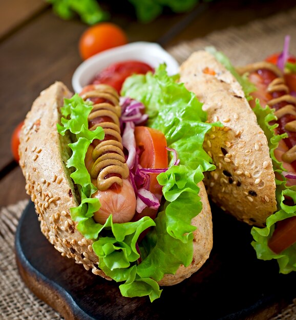 Hotdog mit Ketchup-Senf und Salat auf Holztisch.