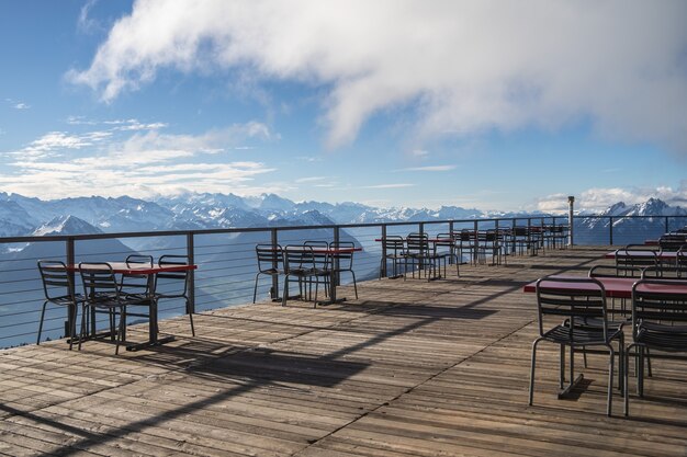 Hotelbalkon mit Tischen und Stühlen mit Blick auf die umliegenden Alpen und Seen an einem wolkigen Tag