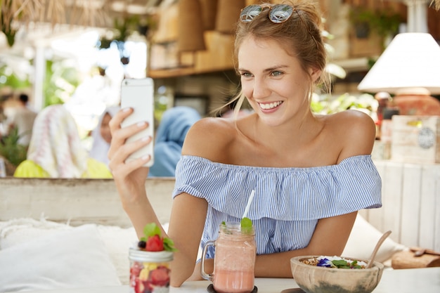 Hübsche blonde Frau, die im Café sitzt