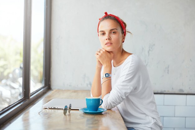 Hübsche blonde Frau, die im Café sitzt