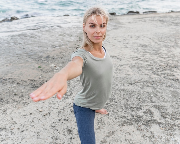 Hübsche blonde Frau, die Yoga im Freien praktiziert