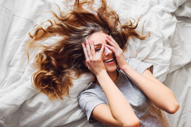 Hübsche blonde Frau haben gut in ihrem Schlafzimmer. Junge Dame genießt ihren Morgen und wacht auf.