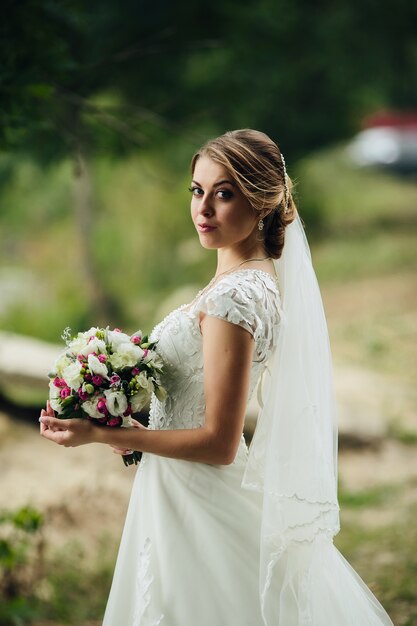 Hübsche Braut posiert mit Bouquet