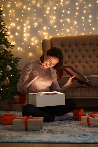 Hübsche brünette Frau öffnet ein entzückendes Geschenk mit Lichtern