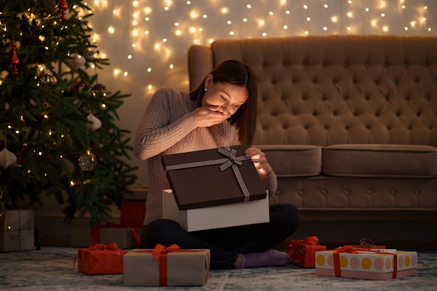 Hübsche brünette Frau öffnet ein entzückendes Geschenk mit Lichtern