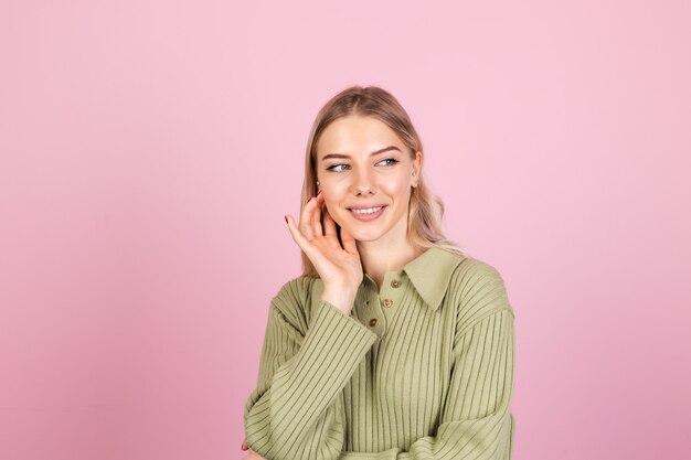 Hübsche europäische Frau im lässigen Pullover auf rosa Wand
