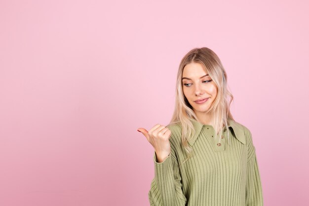 Hübsche europäische Frau im lässigen Pullover auf rosa Wand