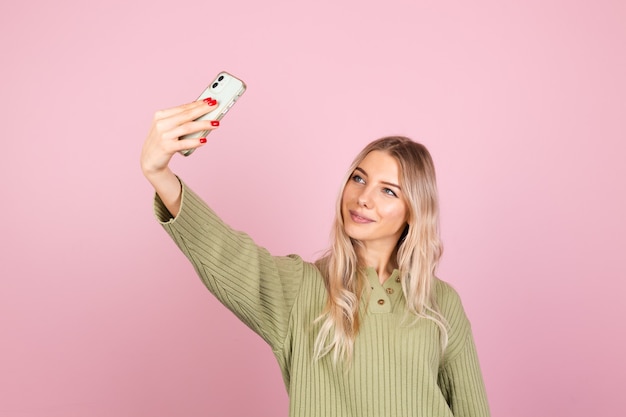 Hübsche europäische frau im lässigen strickpullover auf rosa wand