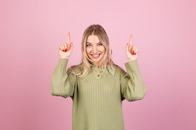 Hübsche europäische Frau im lässigen Strickpullover auf rosa Wand