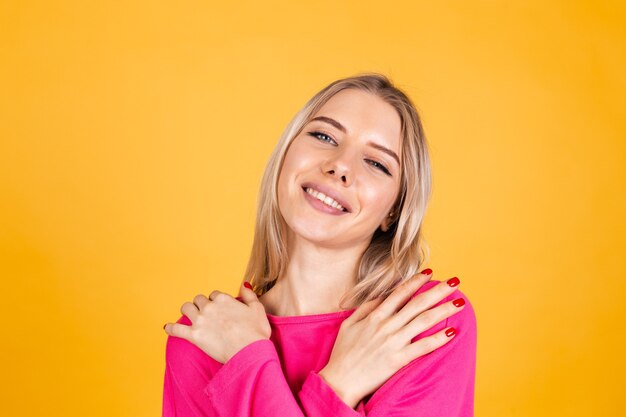 Hübsche europäische Frau in der rosa Bluse auf gelber Wand