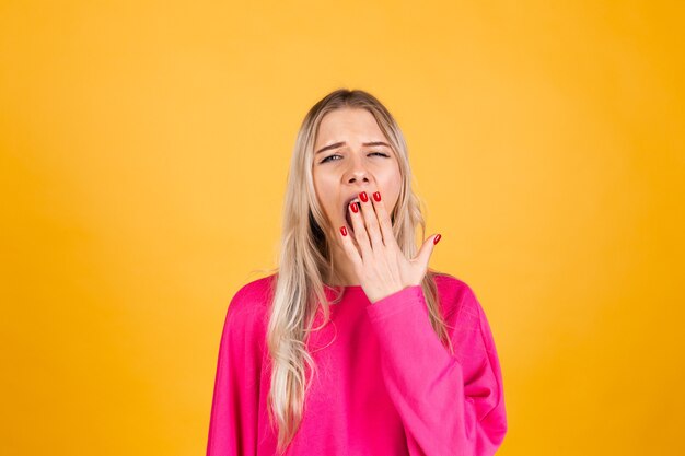 Hübsche europäische Frau in der rosa Bluse auf gelber Wand