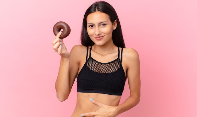 Hübsche fitnessfrau mit einem donut und einer frühstücksschüssel