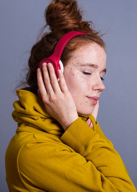 Hübsche Frau der Nahaufnahme mit Kopfhörern und gelbem Hoodie