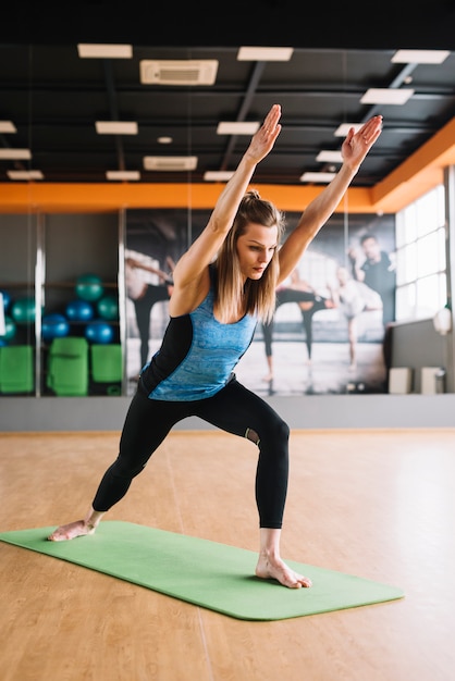 Hübsche Frau, die Arm während des Yoga ausdehnt