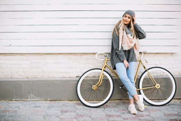 Hübsche Frau, die auf Fahrrad sich lehnt