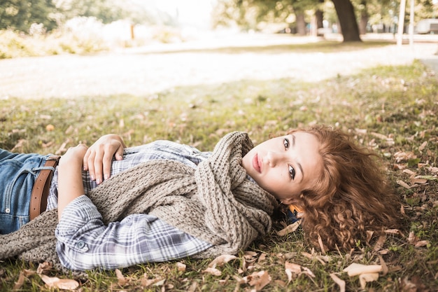 Hübsche Frau, die auf Gras im Park liegt