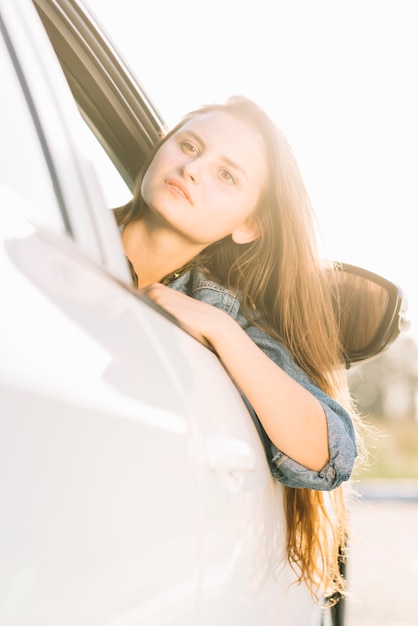 Kostenloses Foto hübsche frau, die aus autofenster heraus hängt