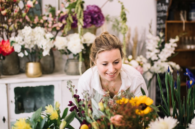 Hübsche Frau, die Blumengestecke schafft