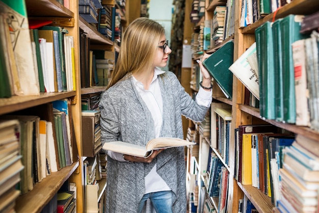 Hübsche Frau, die Buch vom Regal nimmt