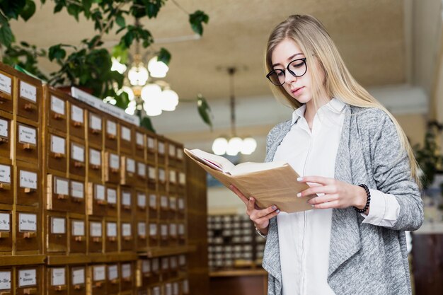 Hübsche Frau, die das Lesen in der Bibliothek genießt