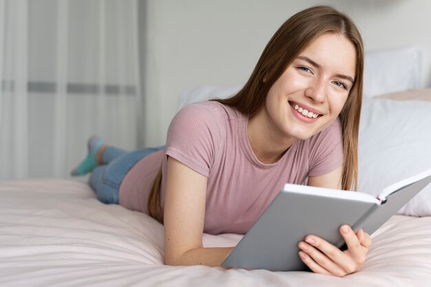 Hübsche Frau, die ein Buch im Bett liest