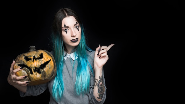 Kostenloses Foto hübsche frau, die furchtsame jack-o-laterne hält